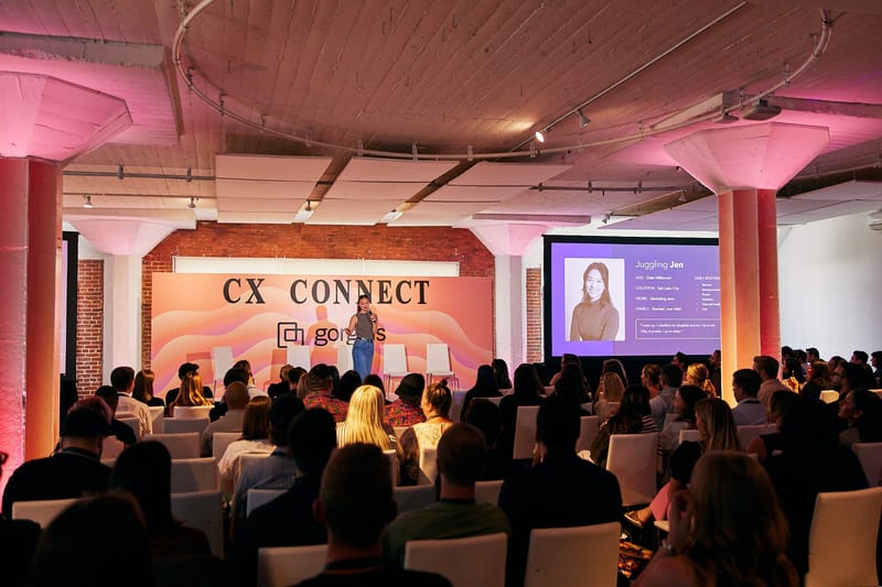 Audience watching a speaker at the CX Connect stage beside a presentation screen