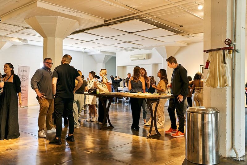 Guests networking around a high wooden table in a loft with mushroom columns and a Gorgias pull-up banner
