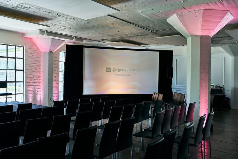 Rows of black chairs facing a large screen reading gorgias partners and #GorgiasPartnerDay