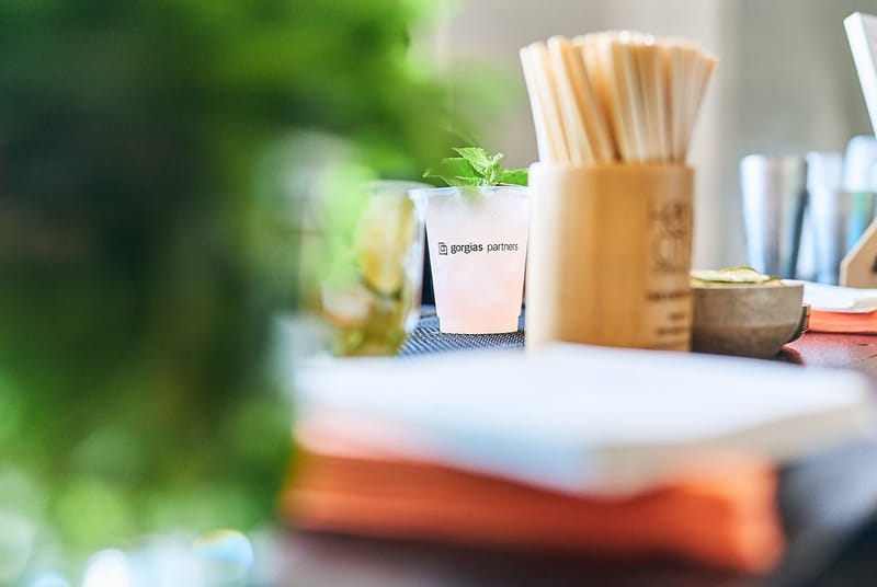 Pink drink with mint in a cup printed gorgias partners beside a wooden straw holder