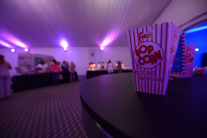 Striped Fresh Popcorn box on a round black table in a tent lit purple and blue