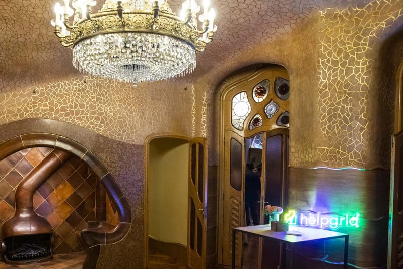 Room with a crystal chandelier, a curved fireplace nook, carved doors and a HelpGrid neon sign