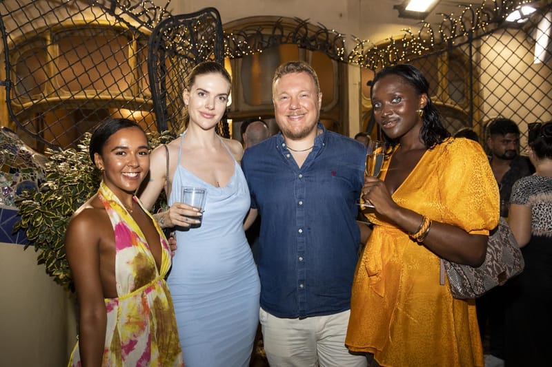 Four guests posing together with drinks