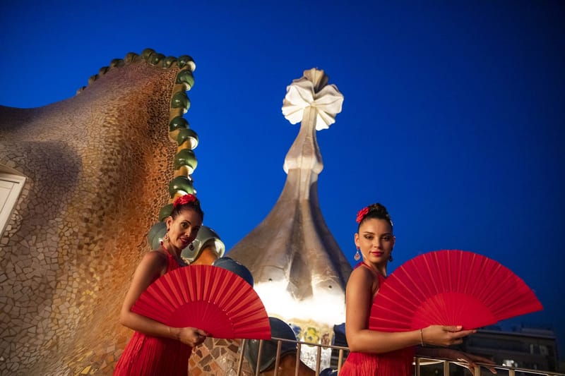 Two dancers with red fans at night beside the scaled roof and a turret