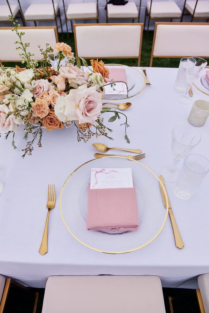 Gold-rimmed glass charger with a pink napkin holding a Superfood Salad Station menu card and gold flatware