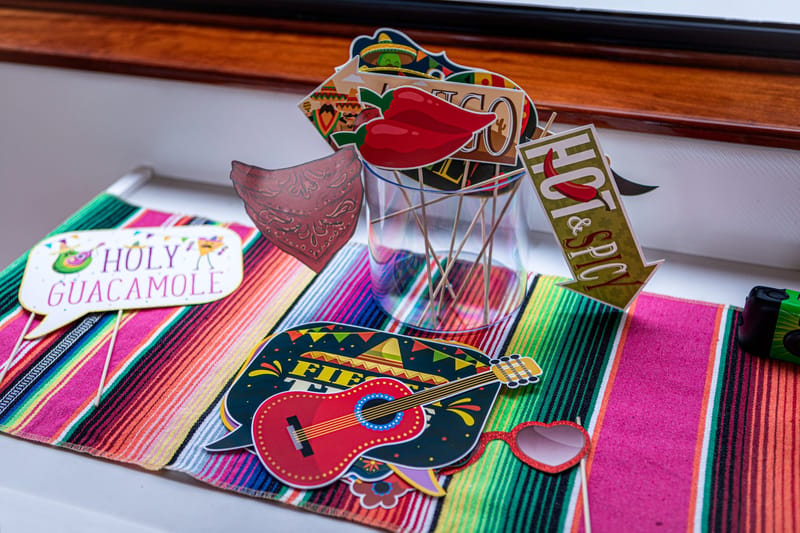Fiesta photo props including Holy Guacamole, Hot & Spicy and a guitar on a striped serape runner