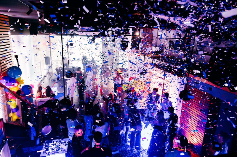 Confetti falling over a crowded, colorfully lit dance floor seen from above