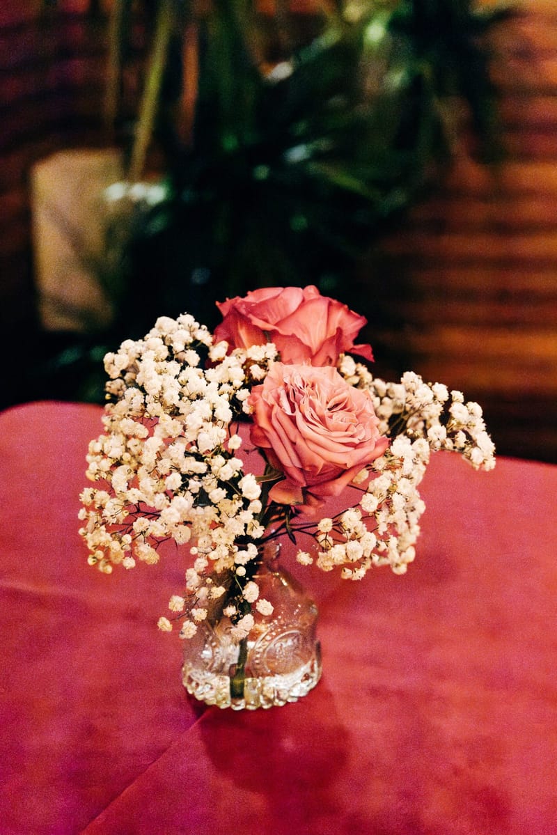 Pink roses and baby's breath in a small glass vase on a red tablecloth