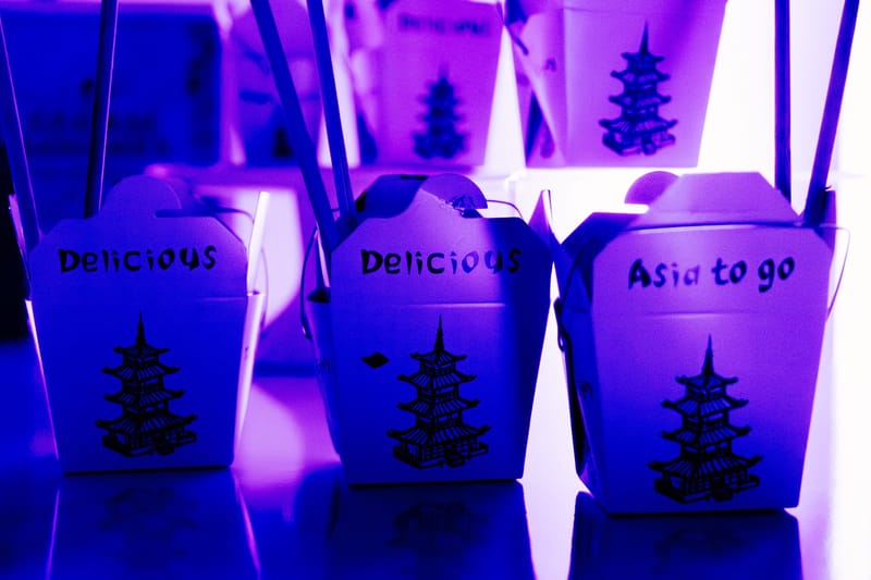 Chinese takeout boxes hand-lettered Delicious and Asia to go under purple light