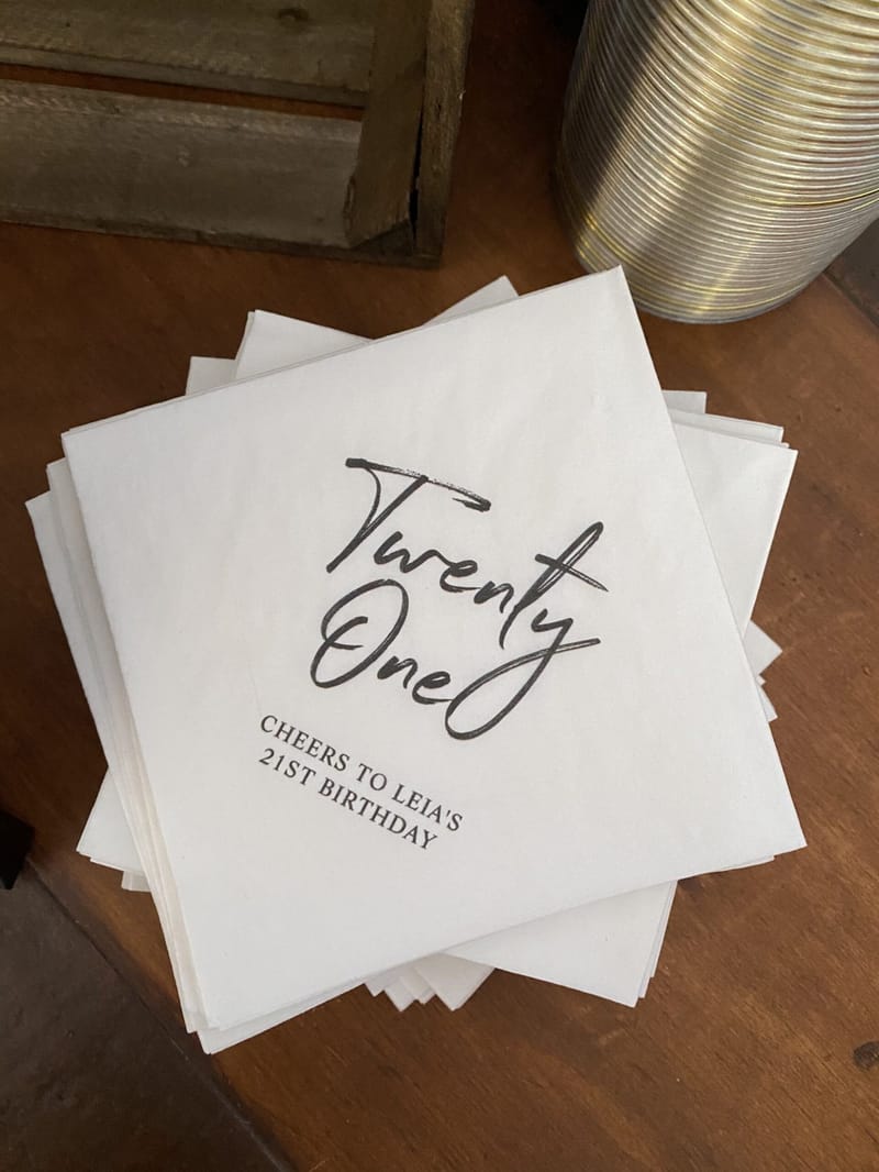 Stack of white napkins printed Twenty One and Cheers to Leia’s 21st Birthday