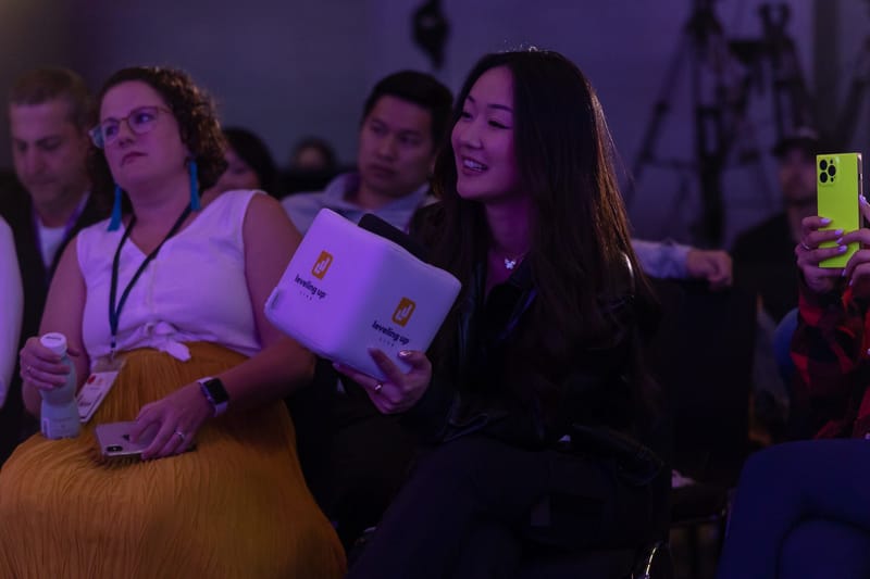Two guests in the audience, one holding a white Leveling Up cube microphone