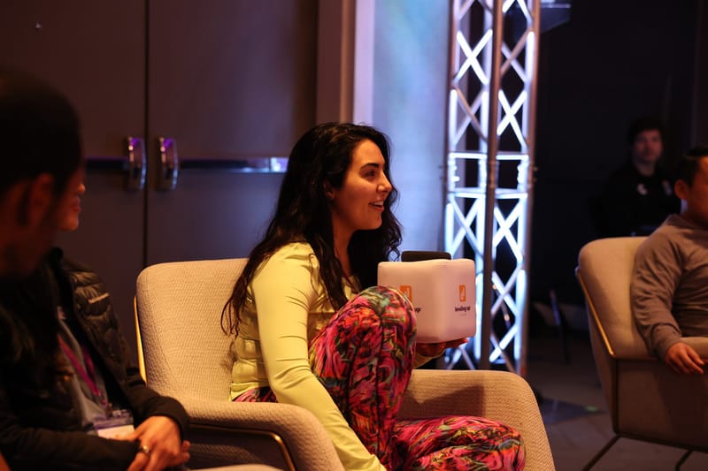 Guest in a bright green top and patterned pants laughing in a cream lounge chair