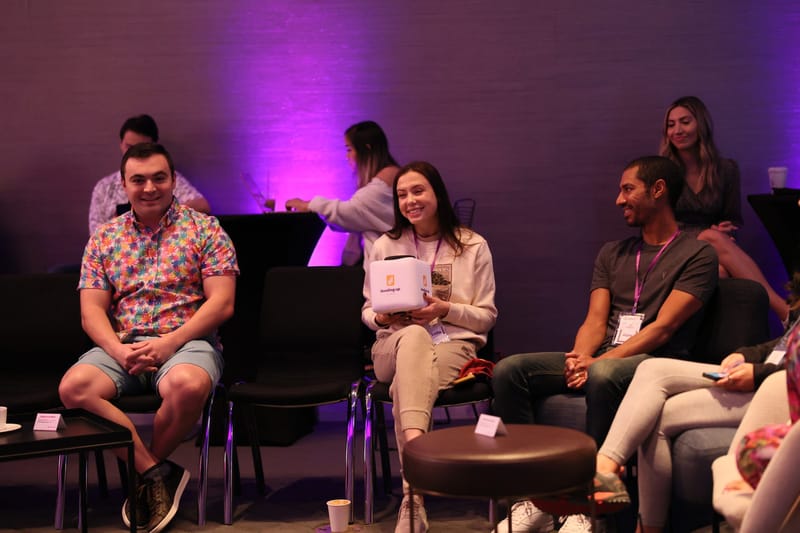 Four guests on chairs and ottomans, one holding a Leveling Up cube microphone