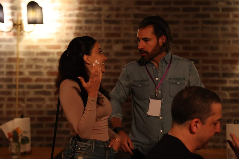 Two guests with lanyards talking in a room with exposed brick walls