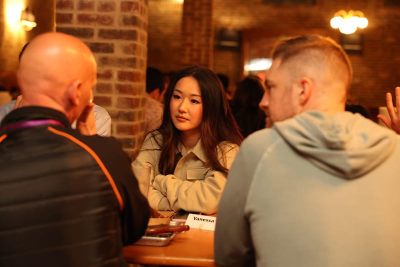 Guests seated around a wooden table with name cards in a brick-walled room