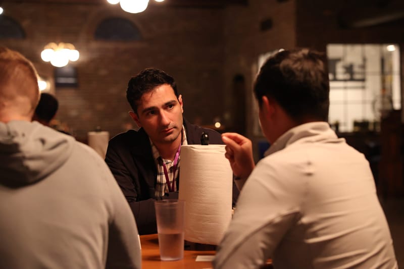 Three guests talking across a table with a paper towel roll and water glasses