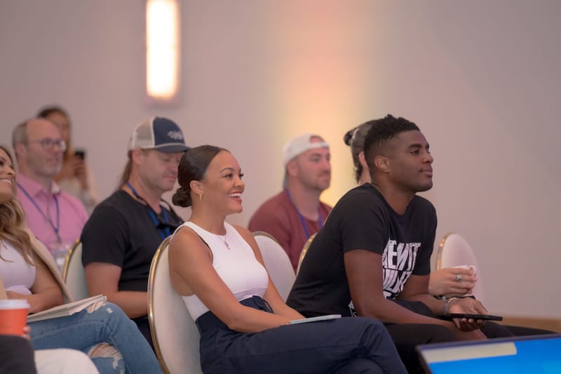 Guests in the audience laughing and listening, one in a white top
