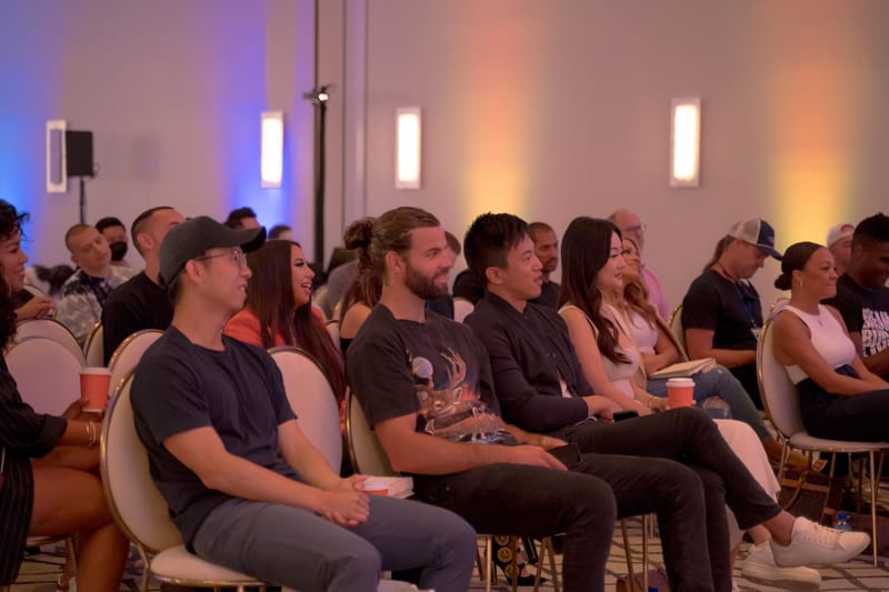 Rows of seated guests watching a session under soft blue and amber lighting