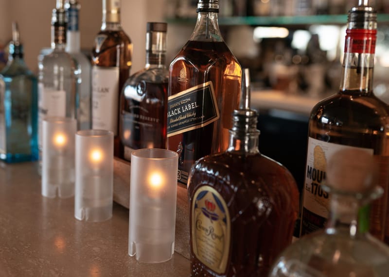 Bottles of spirits including Black Label beside frosted candle holders on a bar