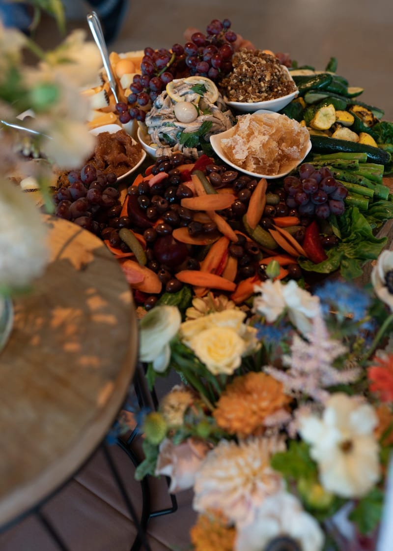Grazing table of grapes, carrots, zucchini and flowers seen from above
