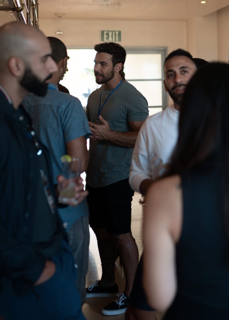 Guests with lanyards talking in a group under an exit sign