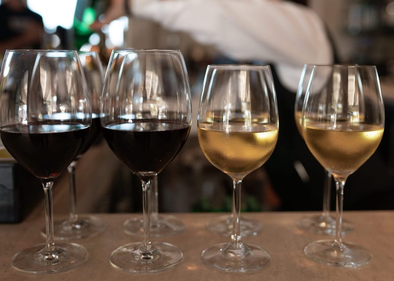 Glasses of red and white wine lined up on a bar