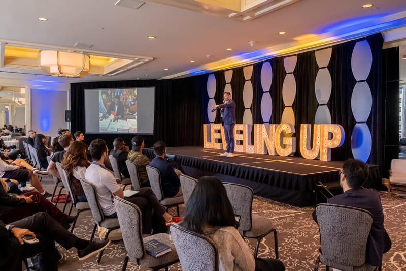 Wide view of the ballroom audience facing a speaker on the LEVELING UP stage