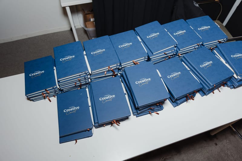 Stacks of navy Creative Connect notebooks on a table