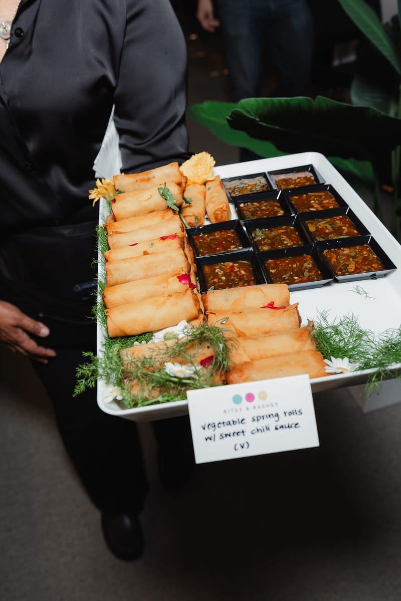 A tray of rolled appetizers and small bites with a menu card