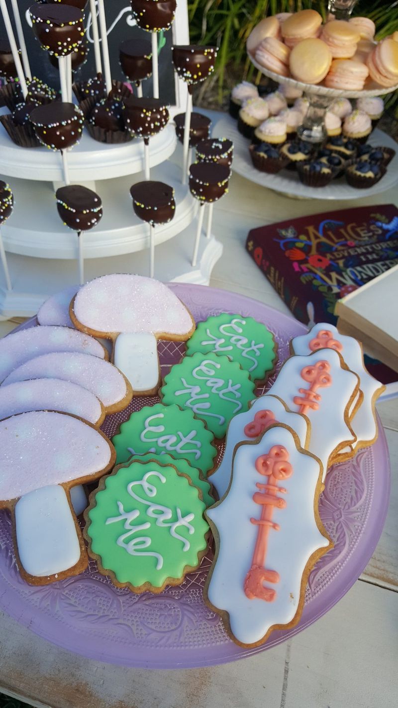 Plate of cookies iced as pink mushrooms, green Eat Me rounds and white plaques with coral keys