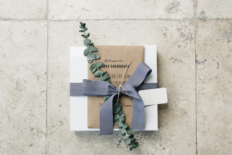 Gift box tied with grey ribbon and eucalyptus, topped with a kraft card reading Welcome to Fort Lauderdale