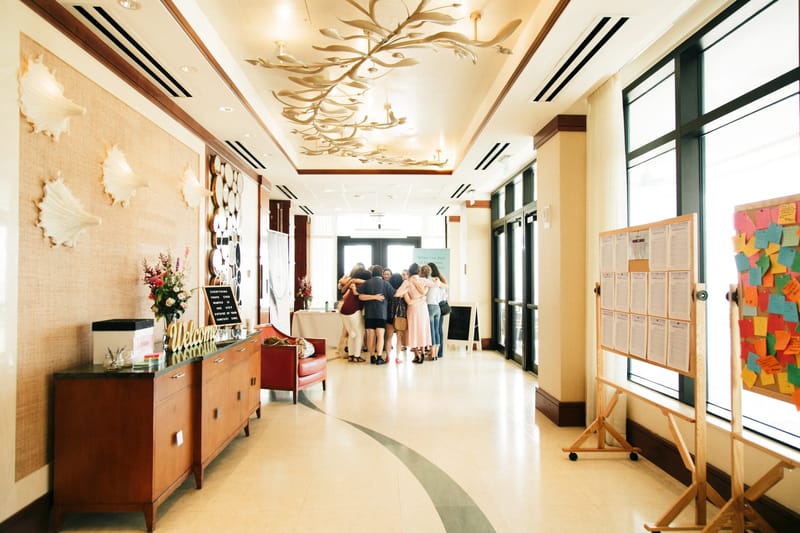 Hallway with shell decor, a dresser with flowers and easels of printed sheets and sticky notes