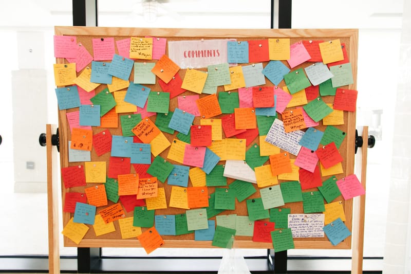 Cork board covered in colored sticky notes under a label reading Comments