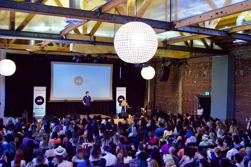 Brick hall hung with giant paper lanterns, a stage screen reading matthew hussey and Matthew Hussey Live banners