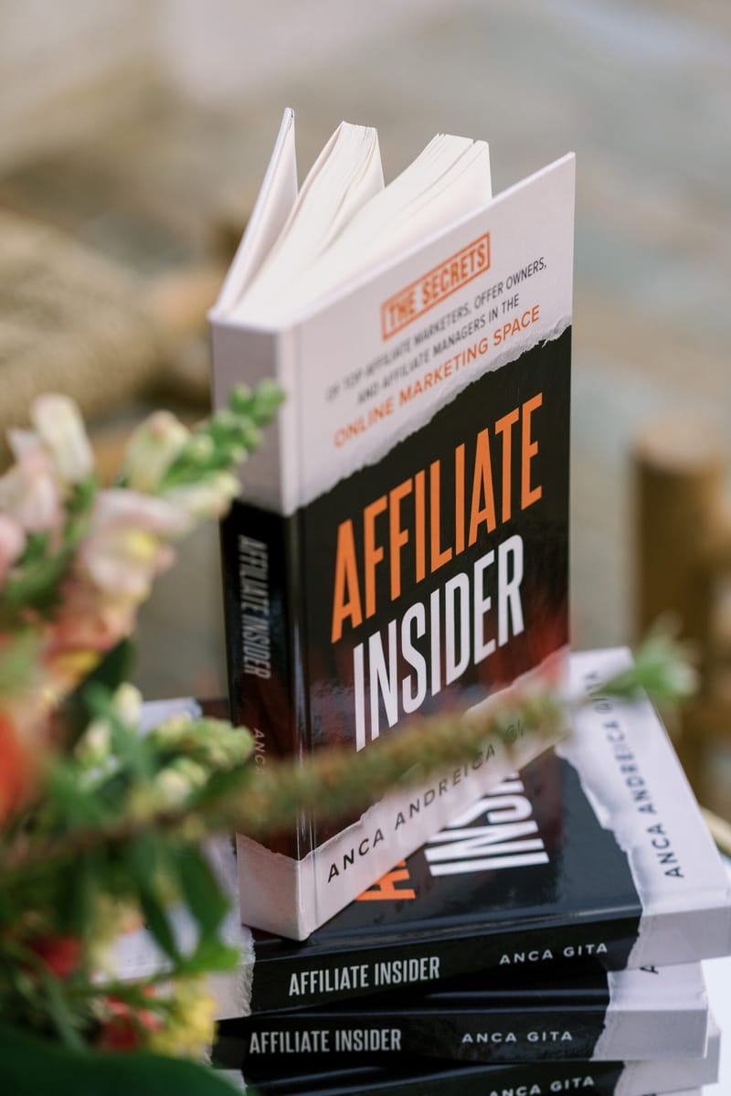 Copy of Affiliate Insider standing open on a stack of the same book beside flowers