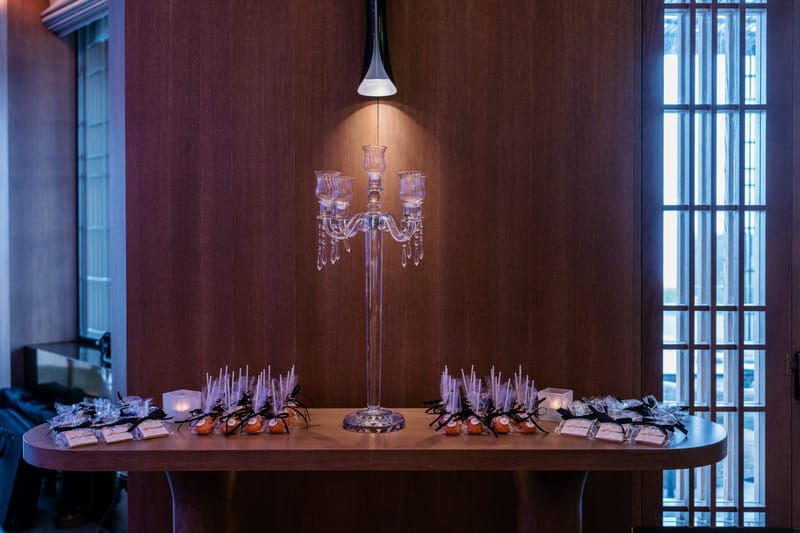 Table of cake pops and maxweb cookies tied with black ribbon under a tall crystal candelabra