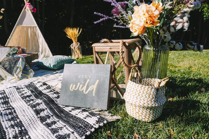 Blue STAY wild sign, a wooden lantern and a woven basket holding a vase of peach flowers