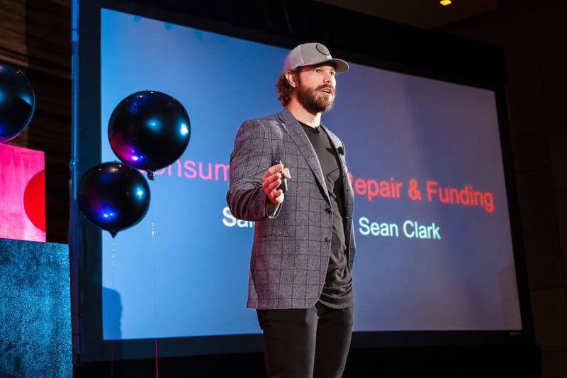 Speaker in a cap and plaid blazer presenting a slide on credit repair and funding