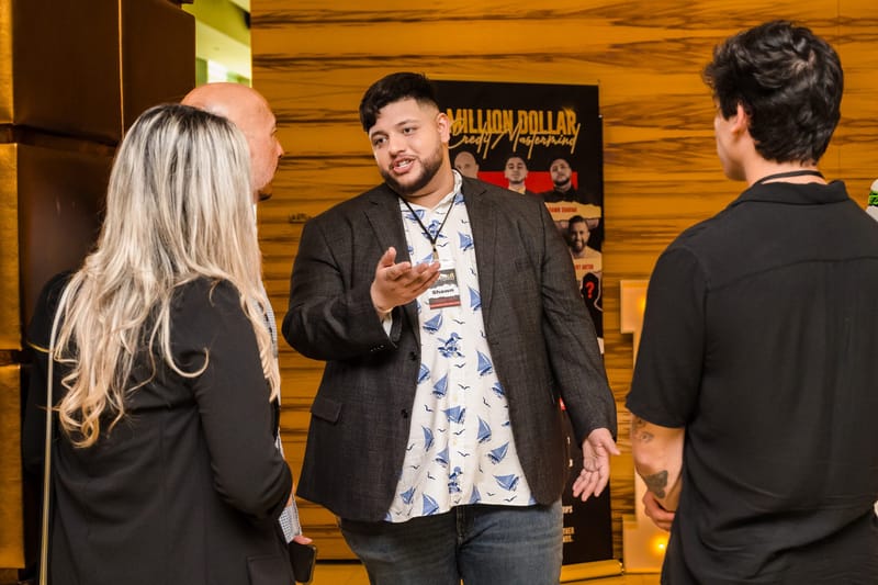 Attendees in lanyards talking in front of a Million Dollar Credit Mastermind banner