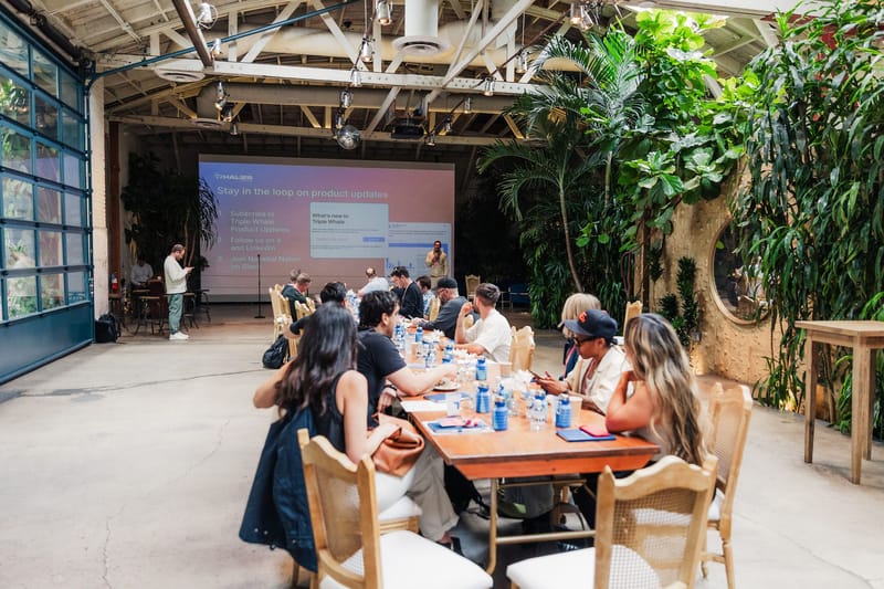 Guests at long tables watching a speaker beside a slide reading Stay in the loop on product updates