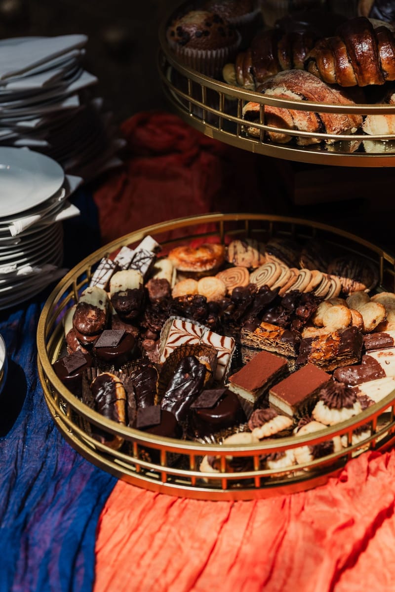 Gold baskets of cookies, chocolates and pastries on blue and orange fabric