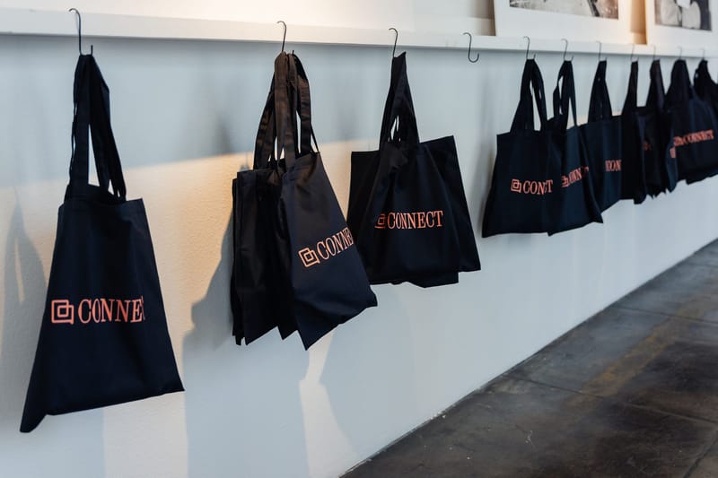 Black Connect tote bags hanging from hooks on a wall