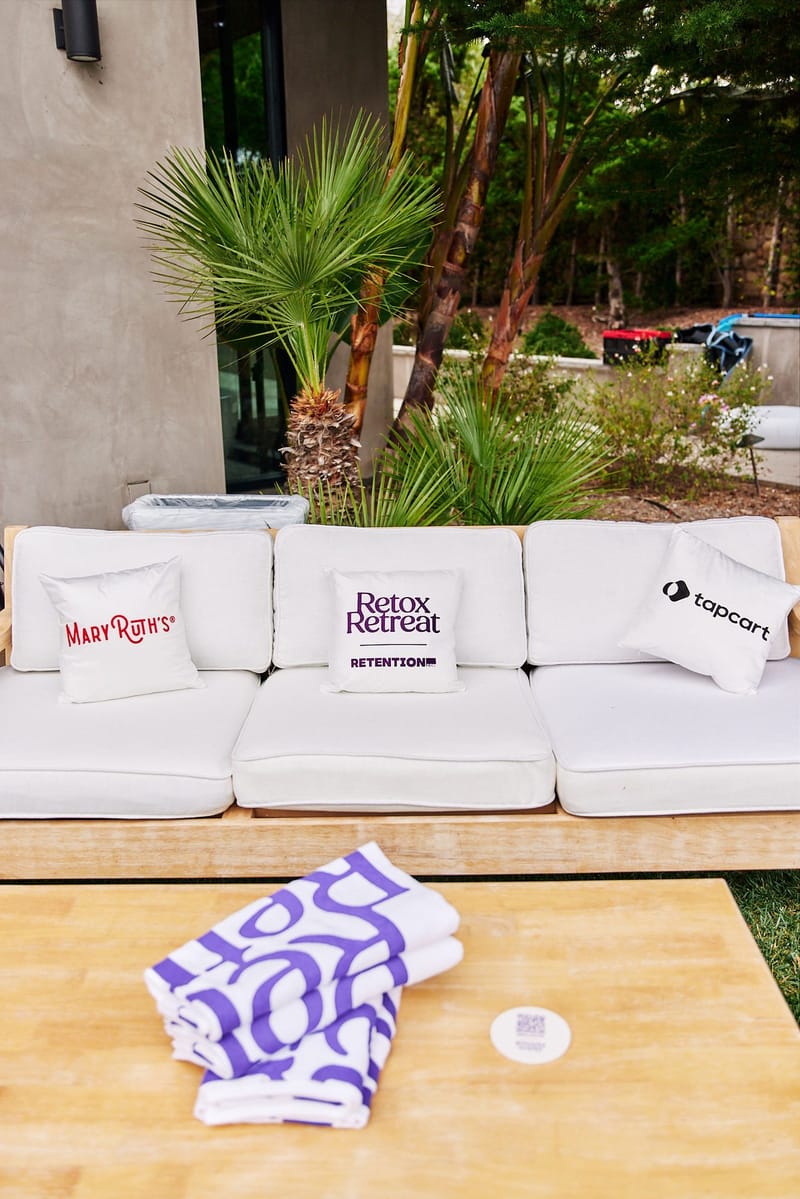 White outdoor sofa with Mary Ruth's, Retox Retreat Retention and tapcart pillows above a purple and white towel