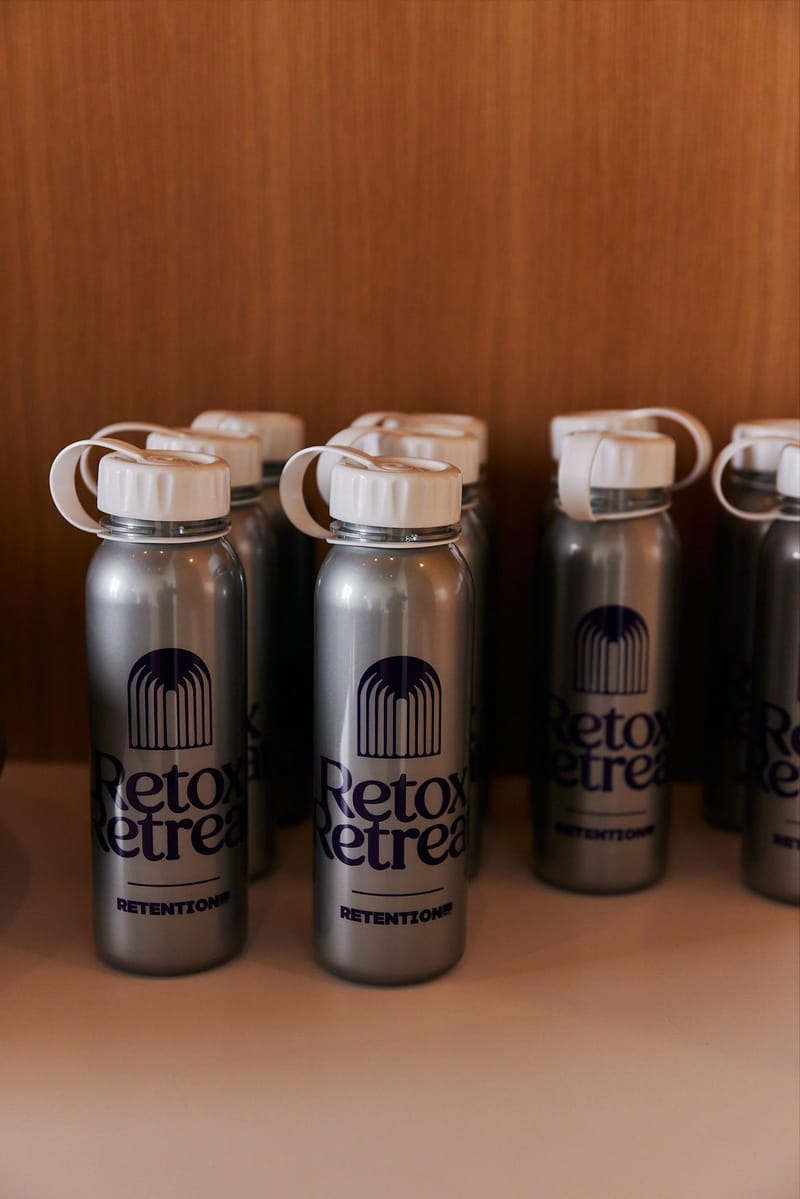 Metal water bottles printed with Retox Retreat and Retention lined up on a wooden shelf