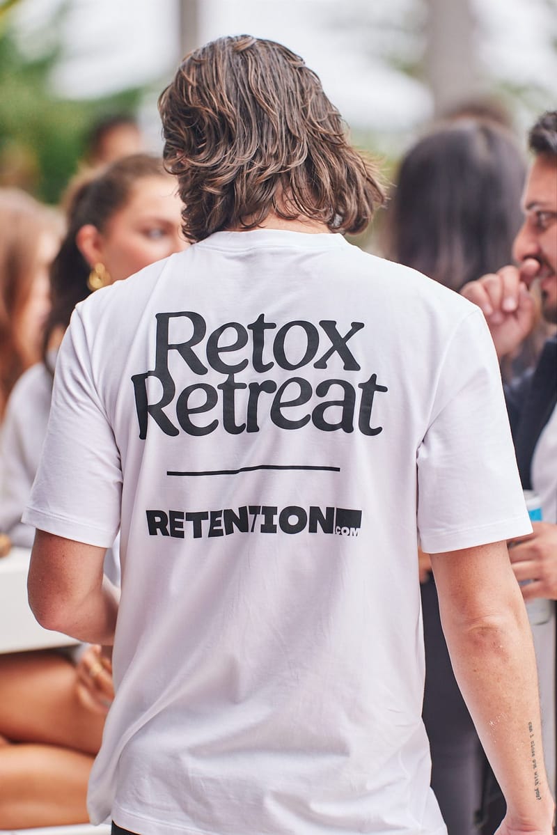 Guest seen from behind in a white Retox Retreat shirt printed with Retention