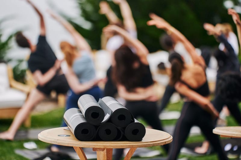 Rolled black yoga mats on a round side table in front of guests reaching overhead