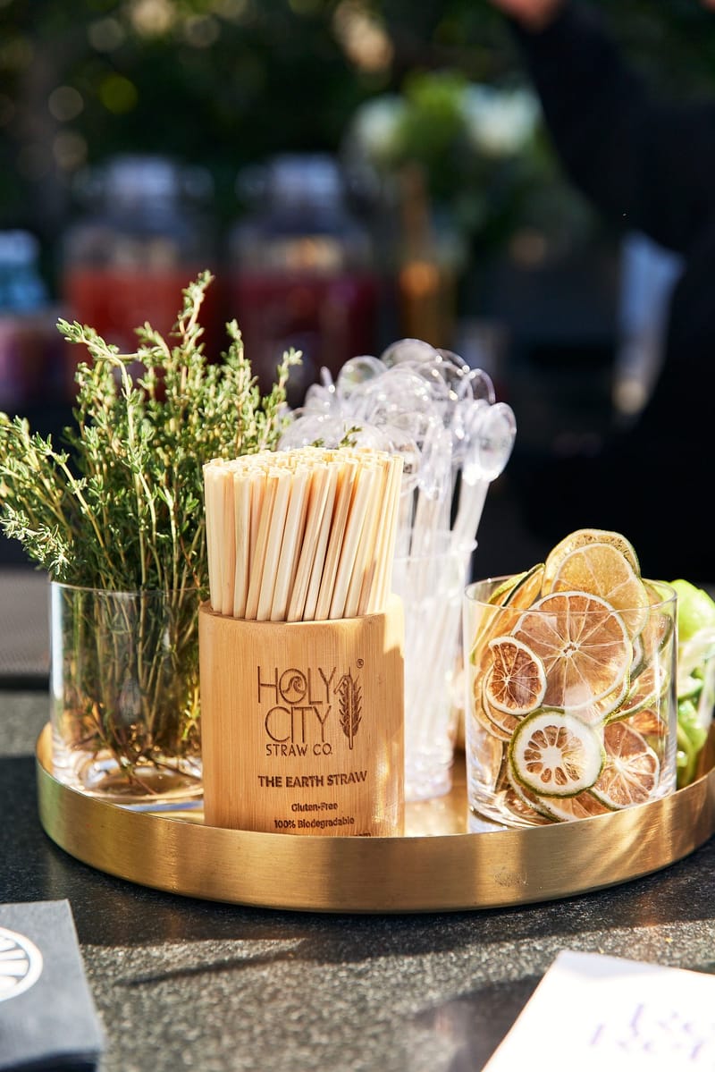 Gold tray with Holy City Straw Co straws, clear stirrers, dried citrus slices and fresh herbs