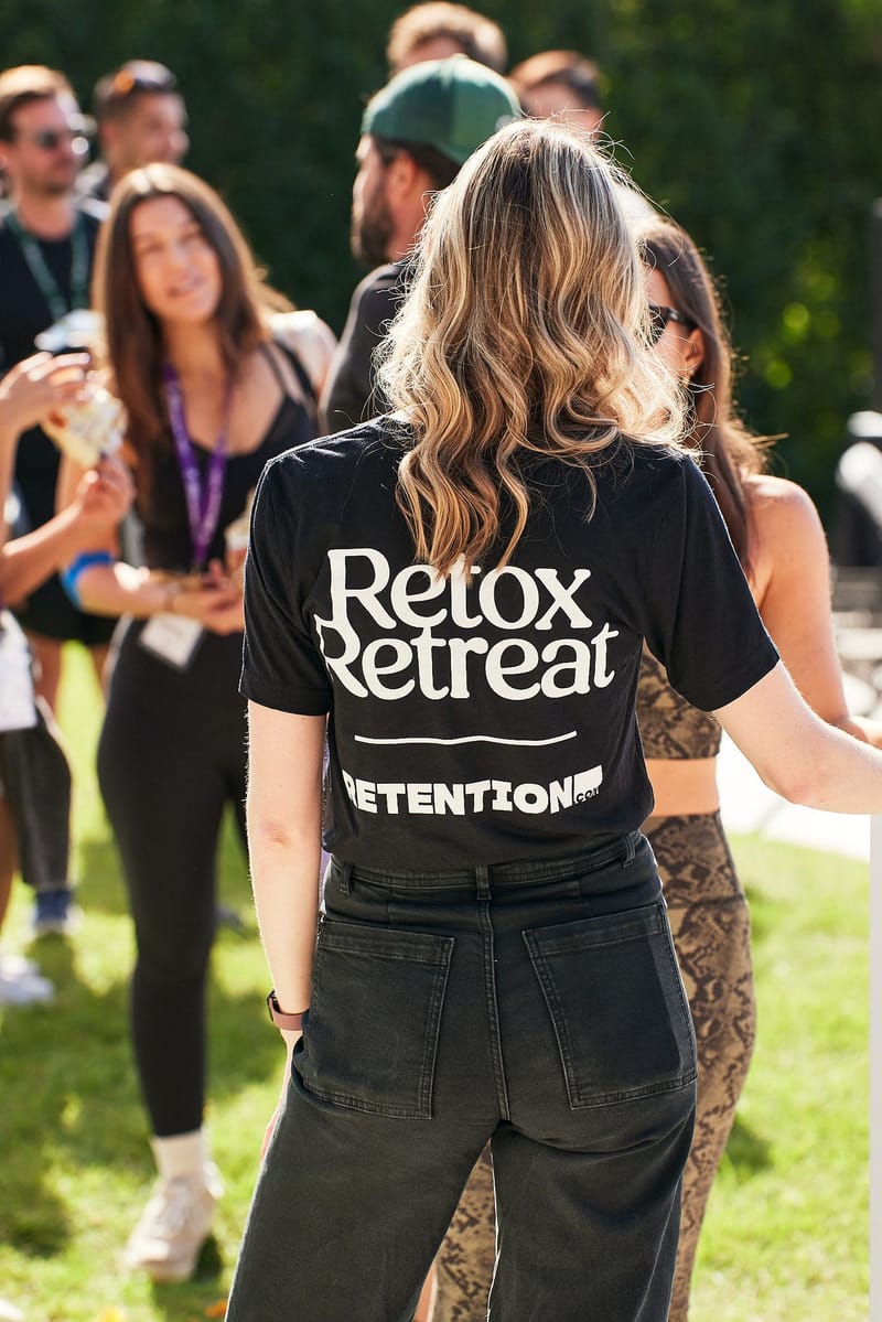 A guest in a Retox Retreat shirt among attendees wearing lanyards on the lawn
