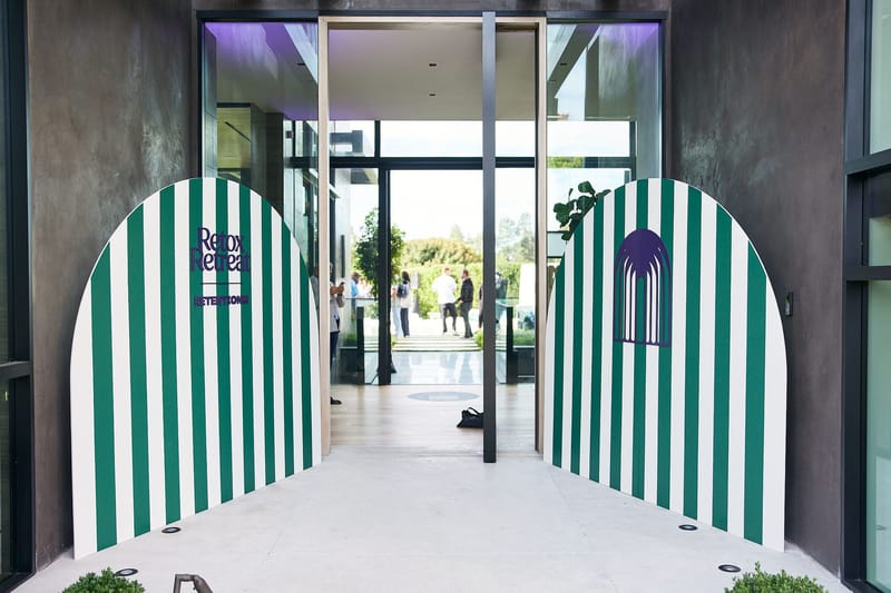 Glass front door of the house framed by two green and white striped arched panels