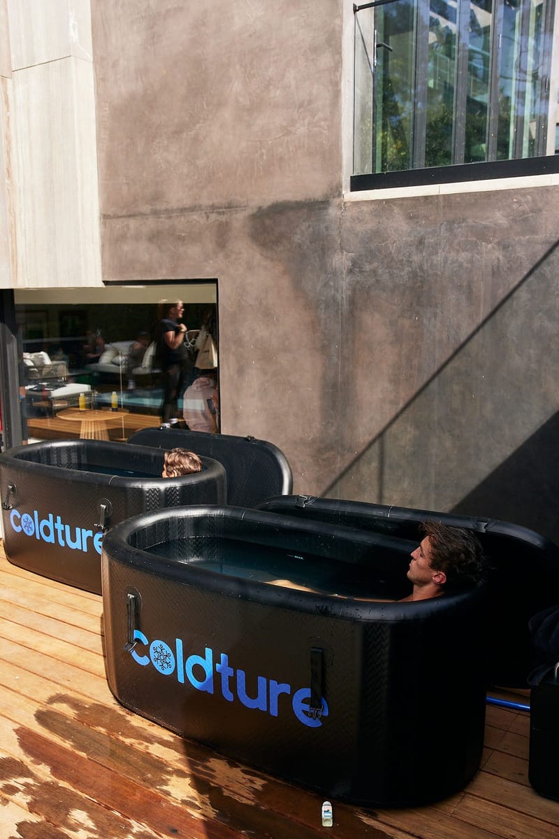A guest sitting in a black Coldture ice bath tub on a wooden deck
